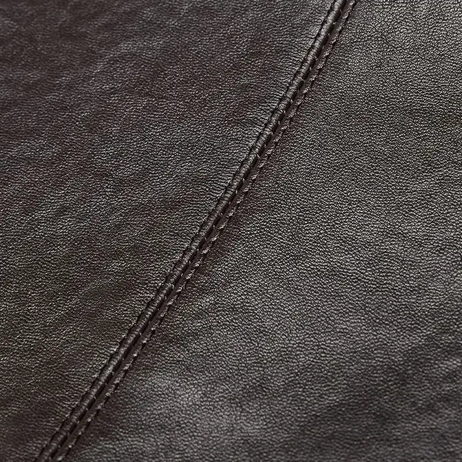 Gros plan sur la texture du cuir marron foncé et les coutures visibles du sac